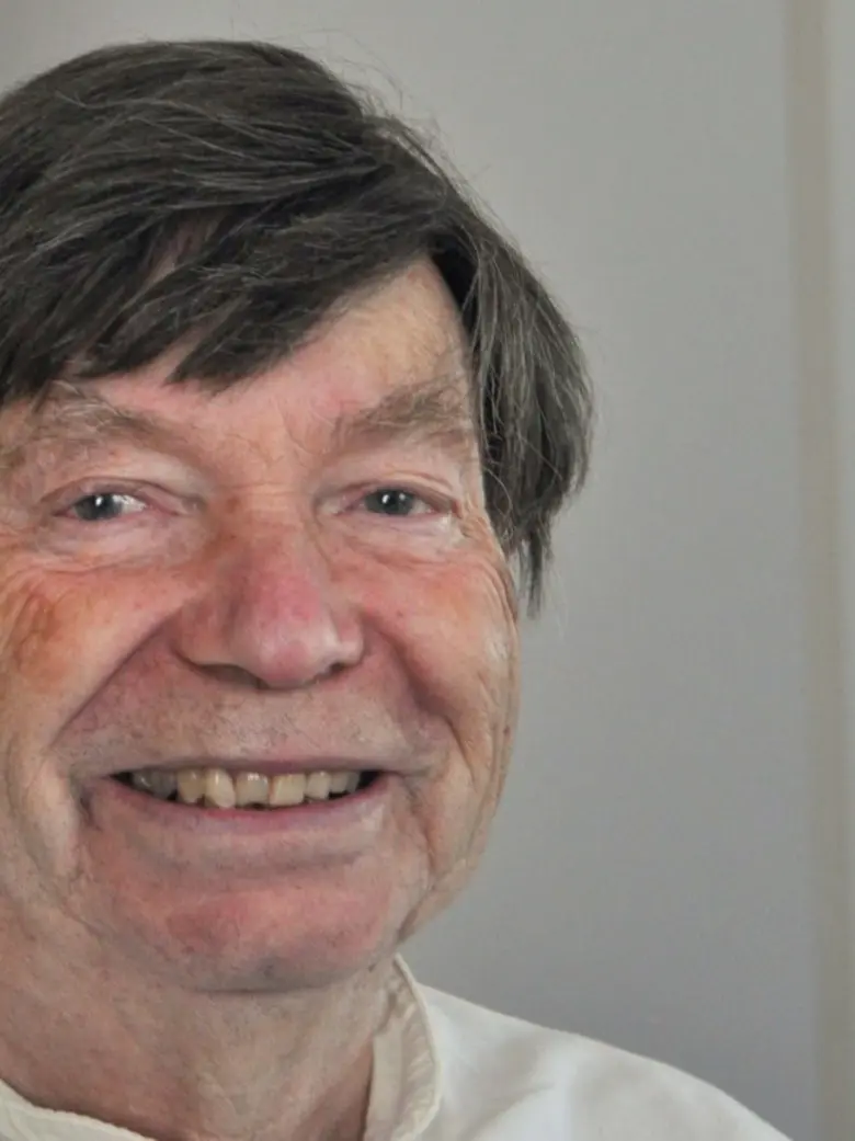 Hans Hermsen, lachend, vor einer hellen Wand