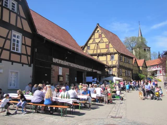 Fest vor der Kelter in Diefenbach: Fachwerkhäuser, lange Biertischreihen mit Gästen, dahinter der Kirchturm
