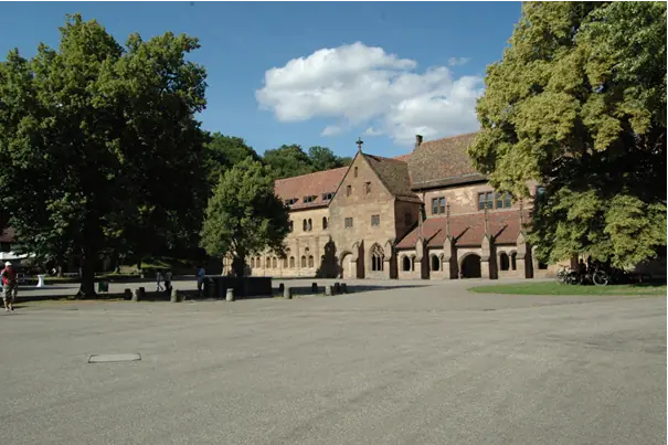 Der weite Klosterhof von Maulbronn mit dem Fachwerkbau und den Arkaden der Klosterkirche, Bäume im Sommerlicht